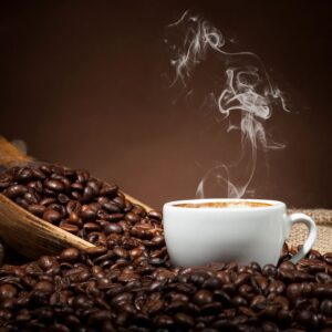 A cup of hot coffee placed on coffee beans